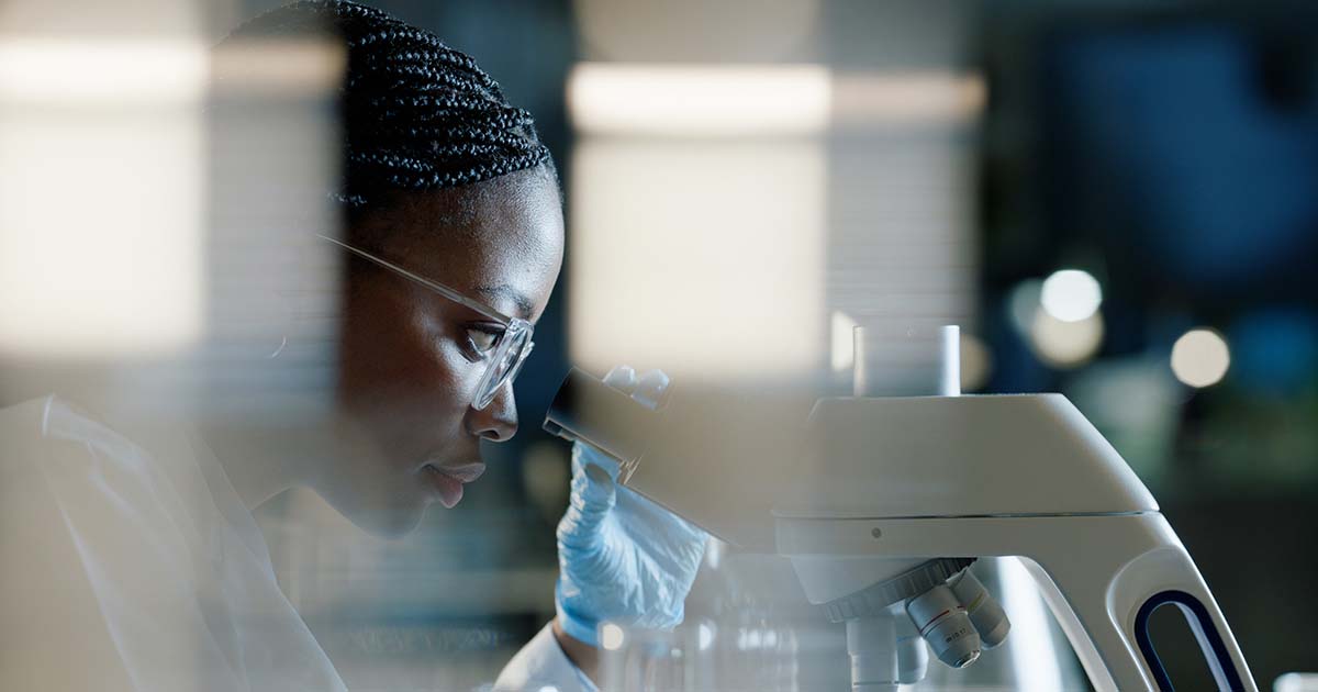 physician looking through microscope for precision medicine