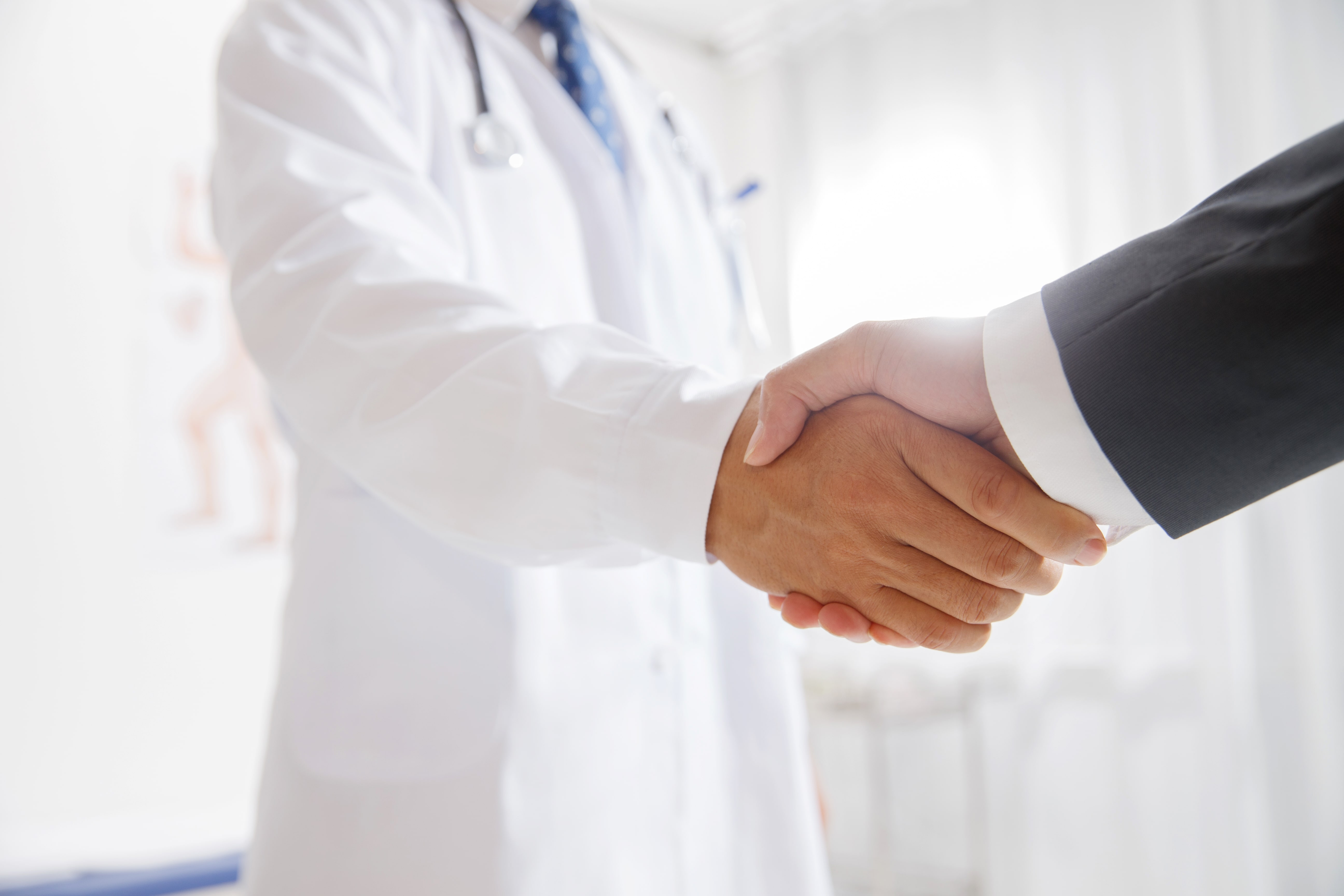 A doctor shaking hands with a businessman.