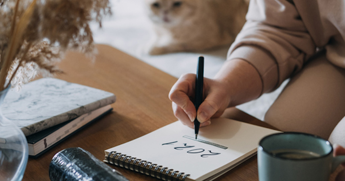 Person writing 2021 on a notepad