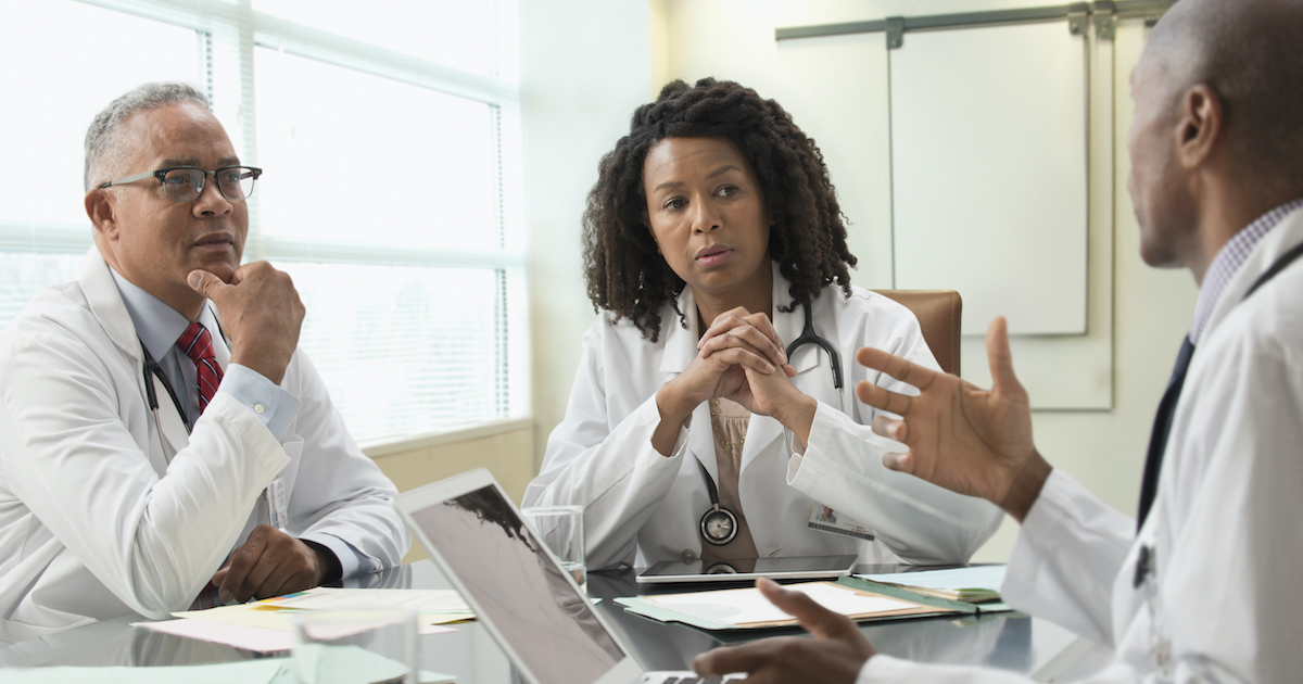 Three doctors discussing among each other in an office meeting