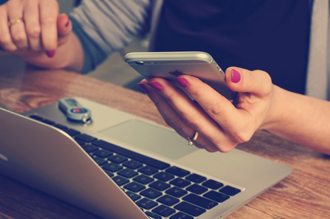 A person using a phone and laptop.