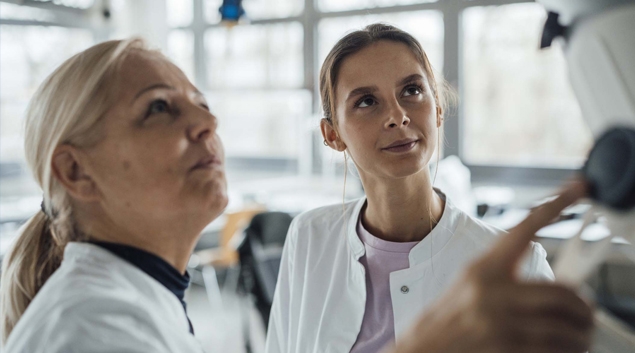 Two people in lab coats work with monitor