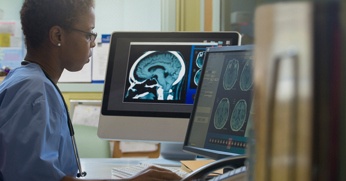Healthcare worker with MRI image working on a computer