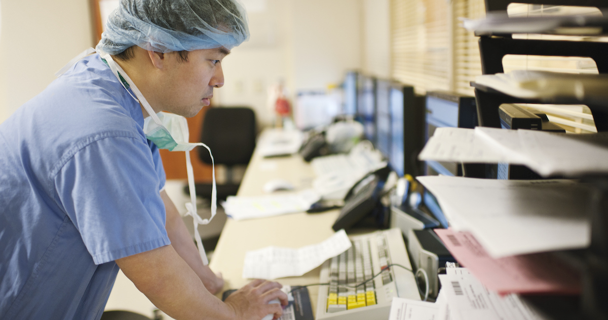 Healthcare worker in scrubs using a computer in office