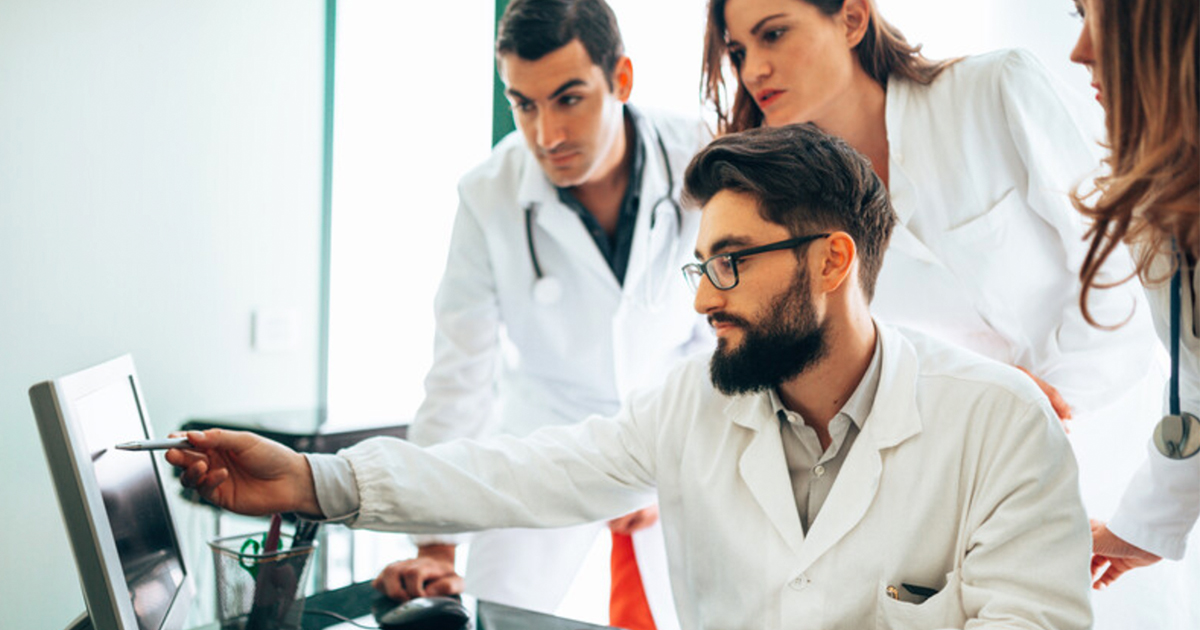 People in medical wear at a screen