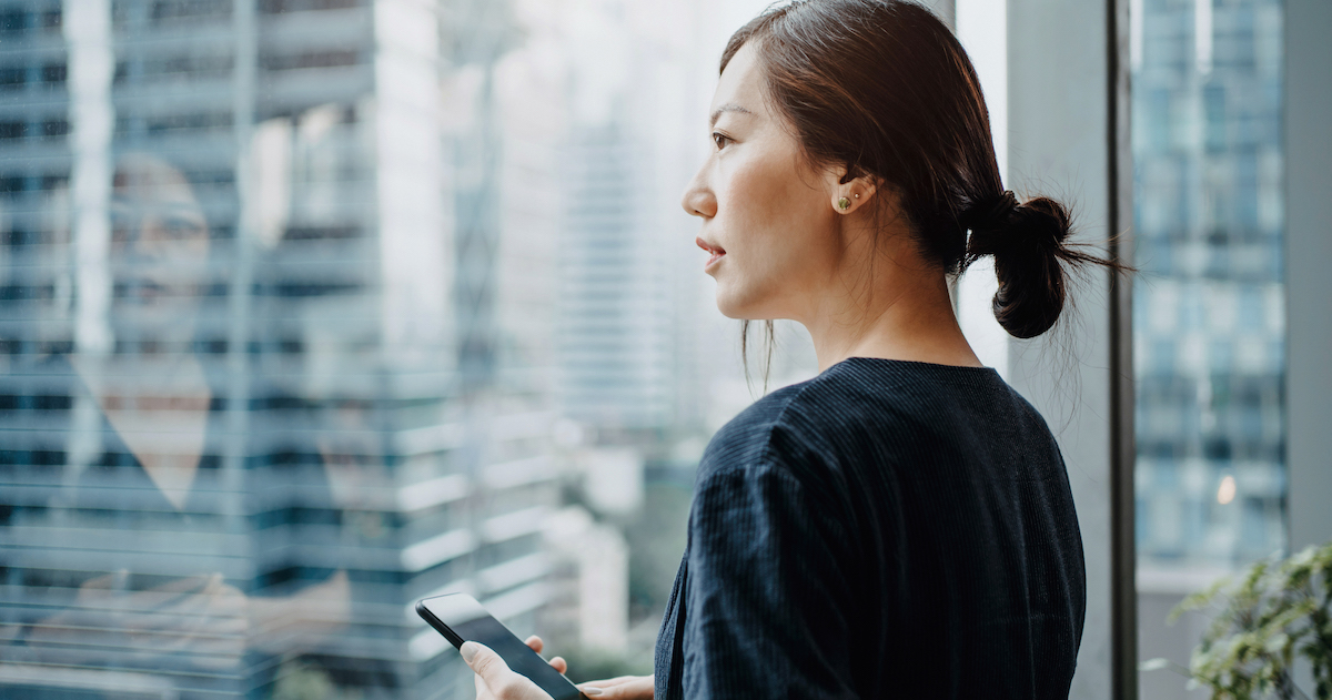 Person with smartphone looking out the window