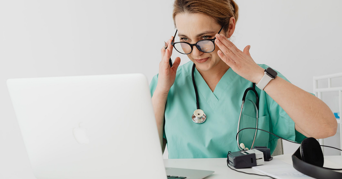 Doctor in scrubs looking at laptop