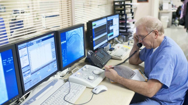 Healthcare working talking on the phone next to computer monitors