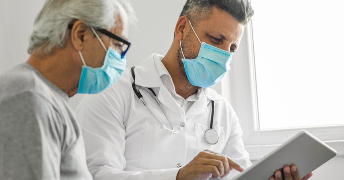 A doctor and patient look at patient records on a tablet.
