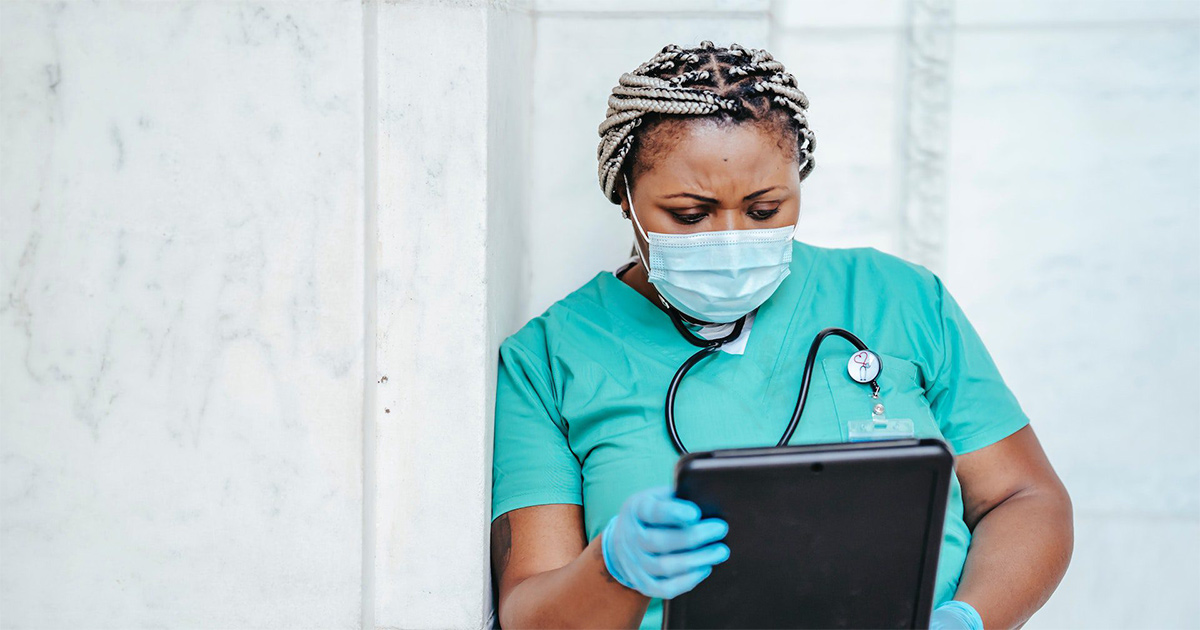 Healthcare worker in mask looking at tablet