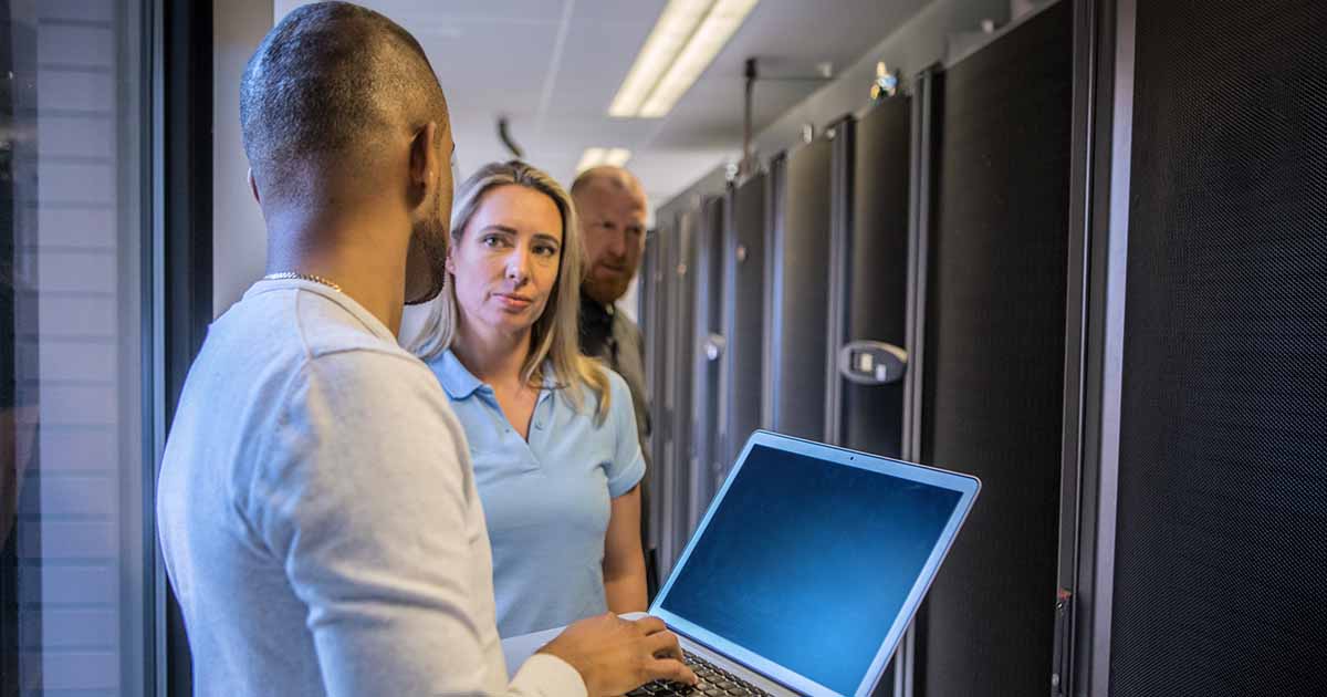 Worker with laptop talking to other IT workers