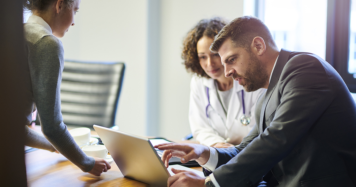 Doctor and businessperson looking at a laptop