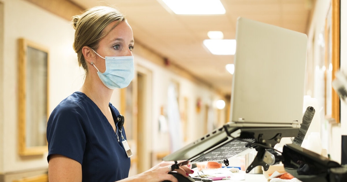 A nurse checking medication records on a laptop