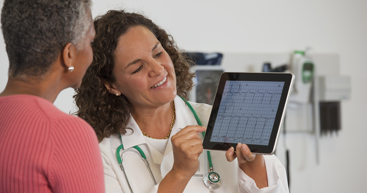 Doctor showing cardiogram on tablet to patient