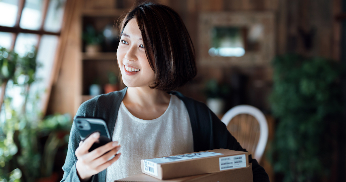 Person holding a package and smartphone