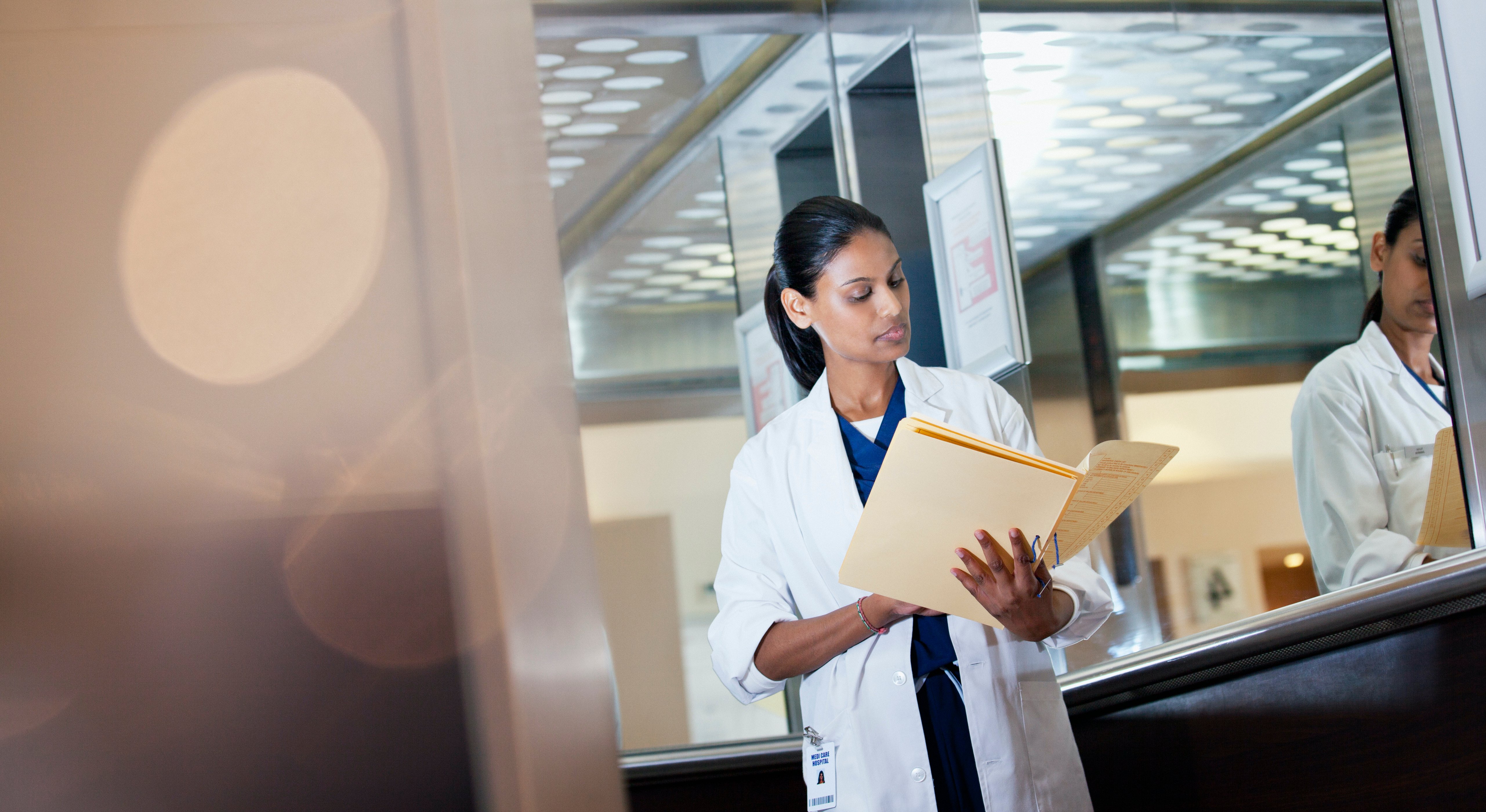 A doctor reading a patient's paper records in a folder