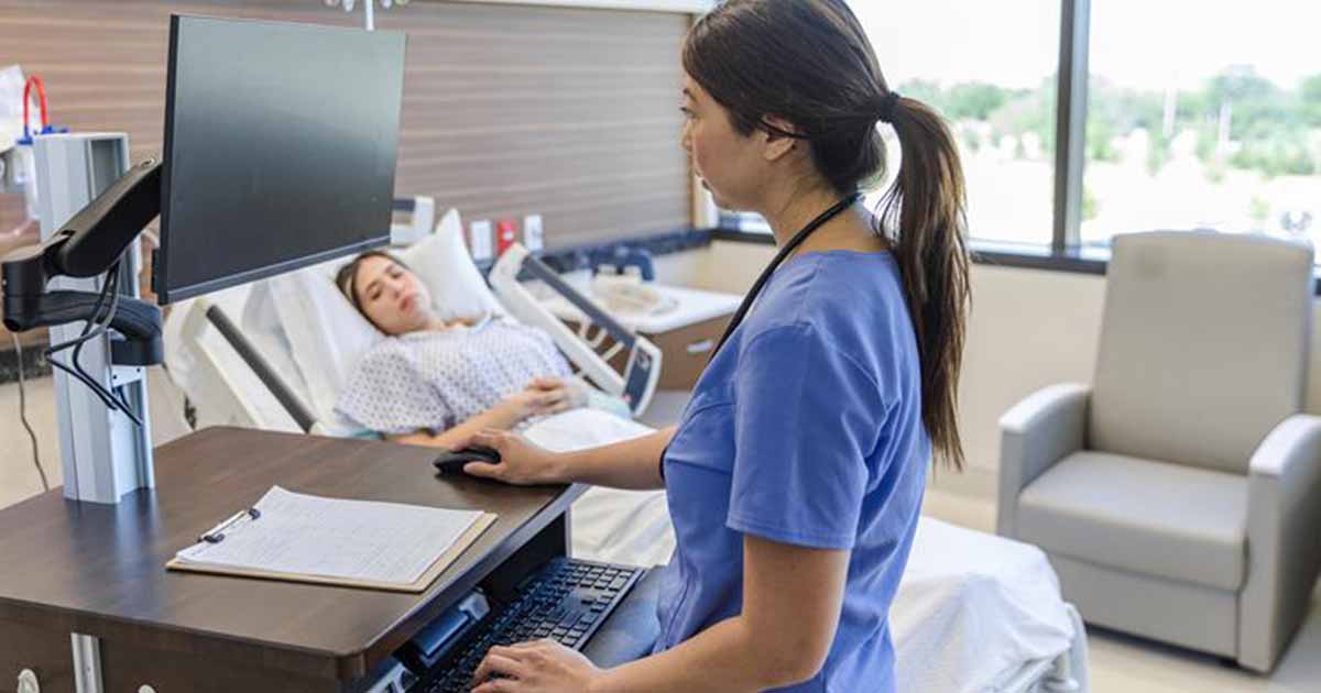 Nursing using laptop in hospital room with patient