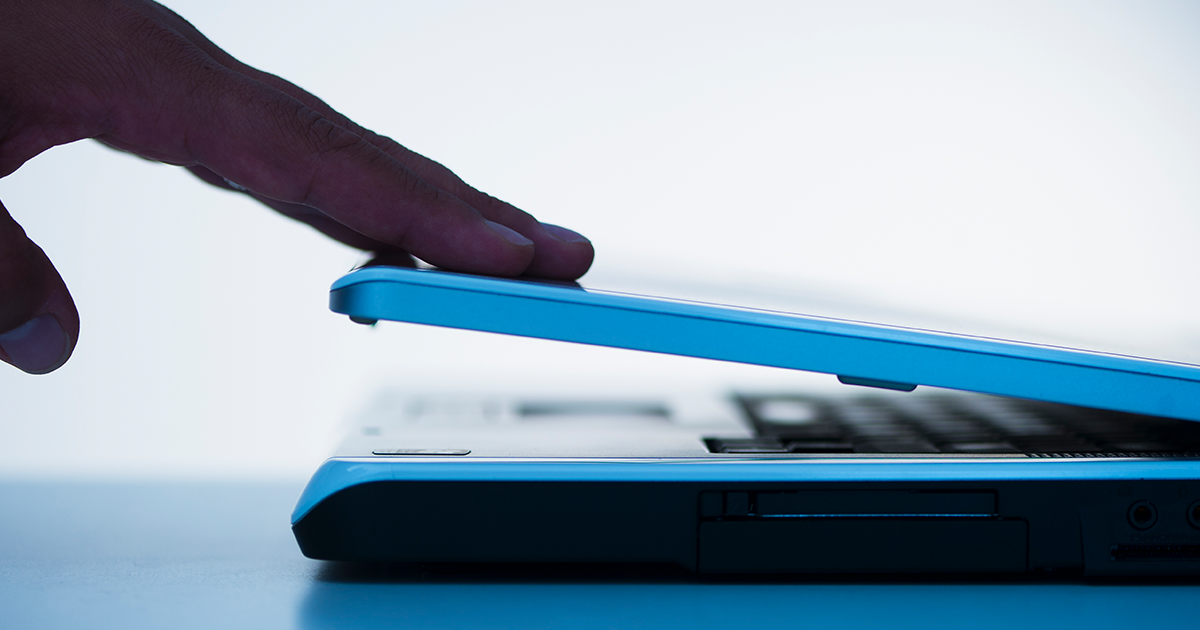 Hand closing a laptop