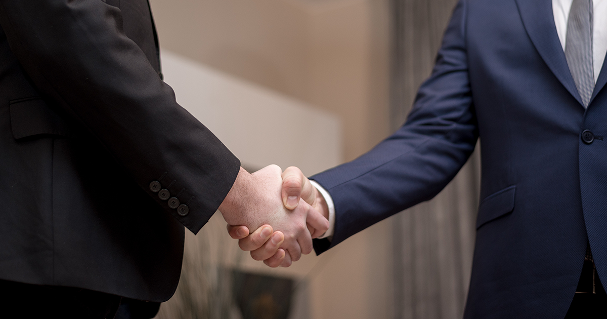Two men in suits shake hands