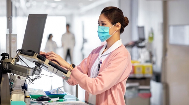 Healthcare worker in mask entering data
