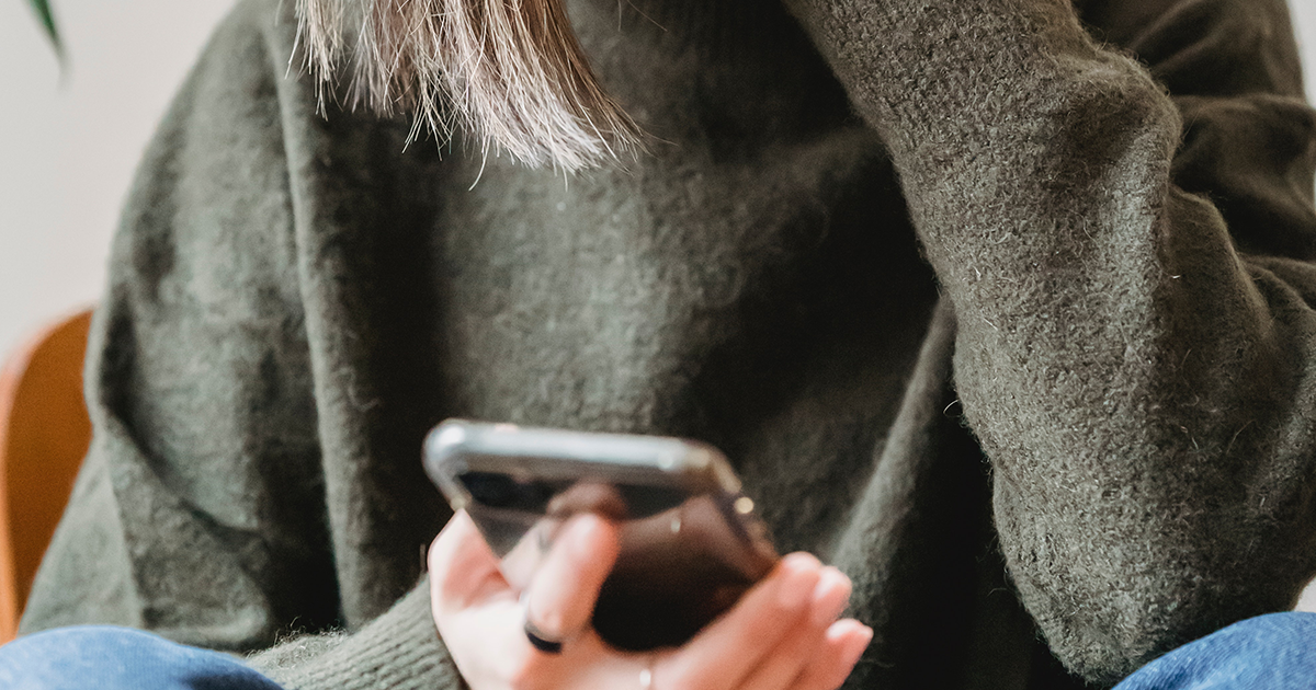 Mobile phone in the hands of a person in green sweater