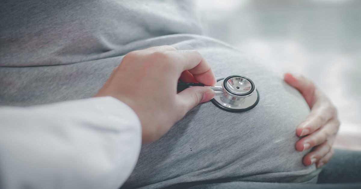 Doctor using stethoscope on pregnant patient's belly