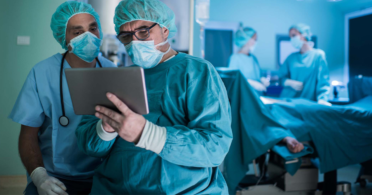 Surgeons looking at a tablet with operating room in background