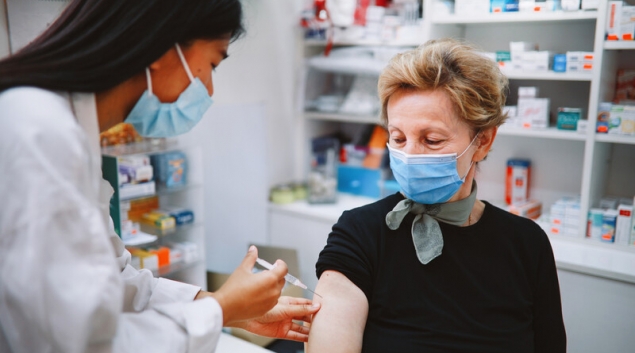 Healthcare worker in mask giving shot to patient in mask