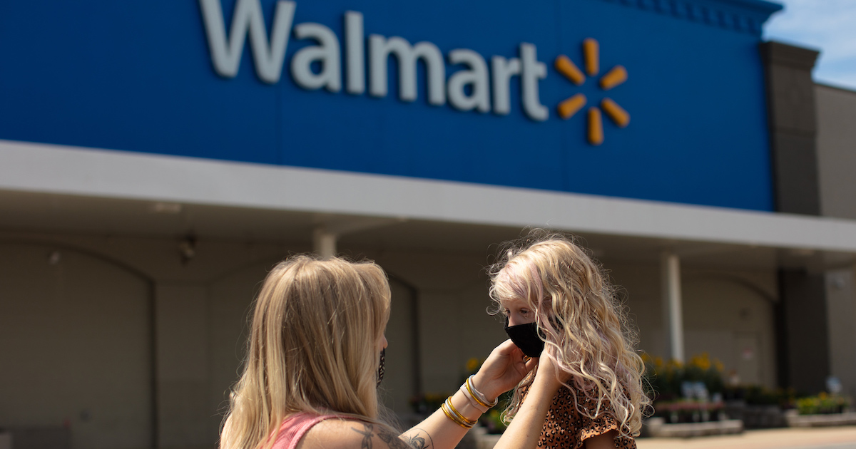 Parent putting mask on their child in front of a Walmart