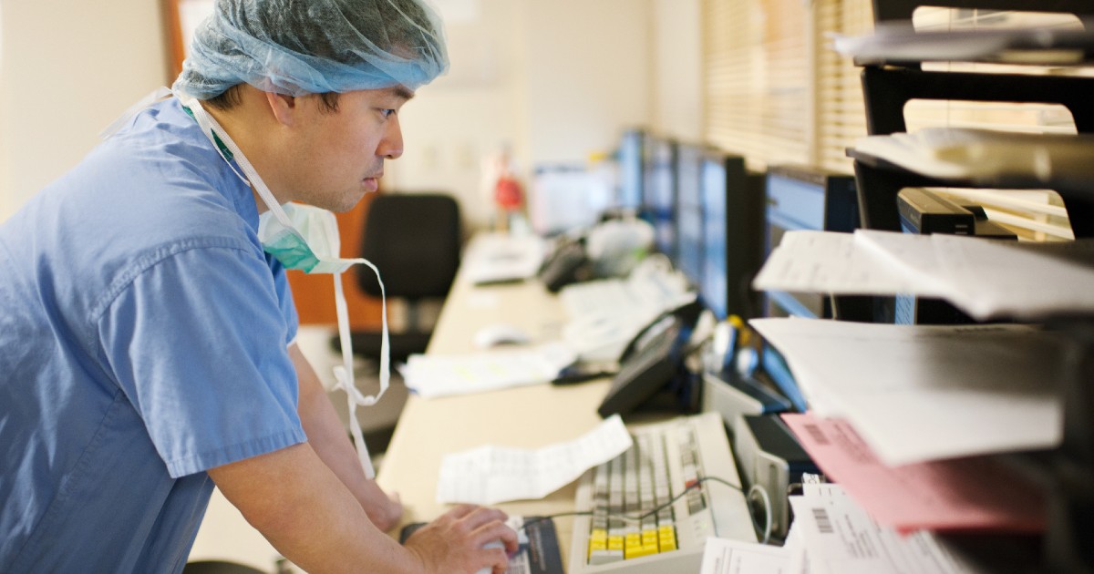 A clinician in scrubs looking at a computer
