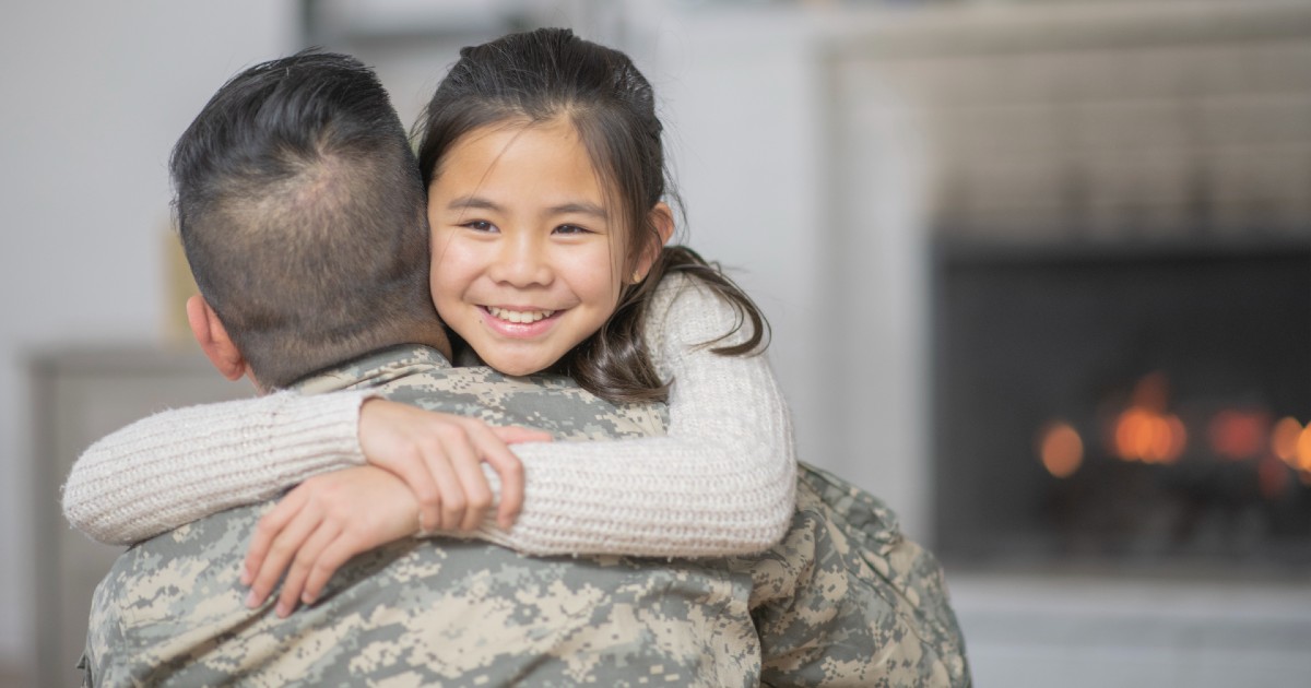 A parent in a military uniform hugging their child