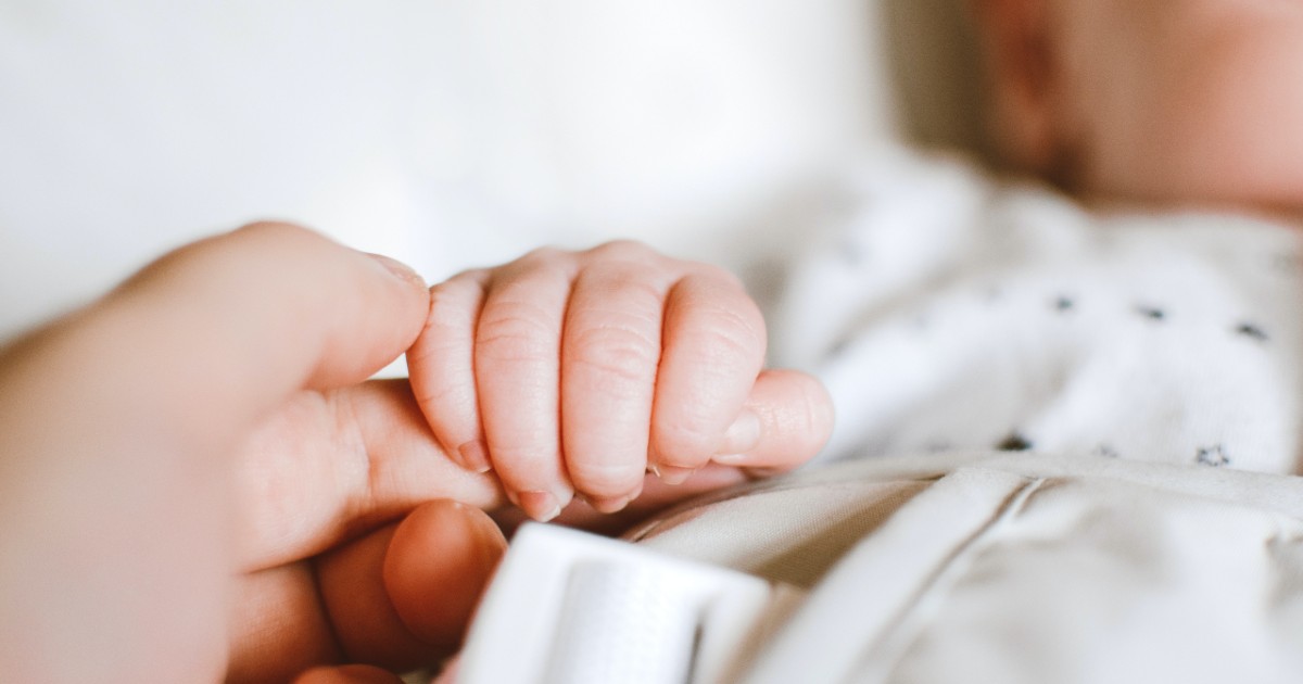 A baby grabbing an adult's finger