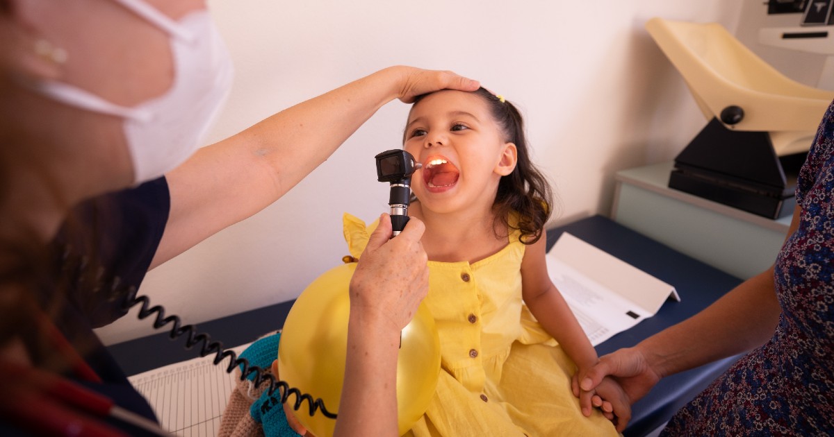 A clinician looking inside a child's mouth at a medical appointment