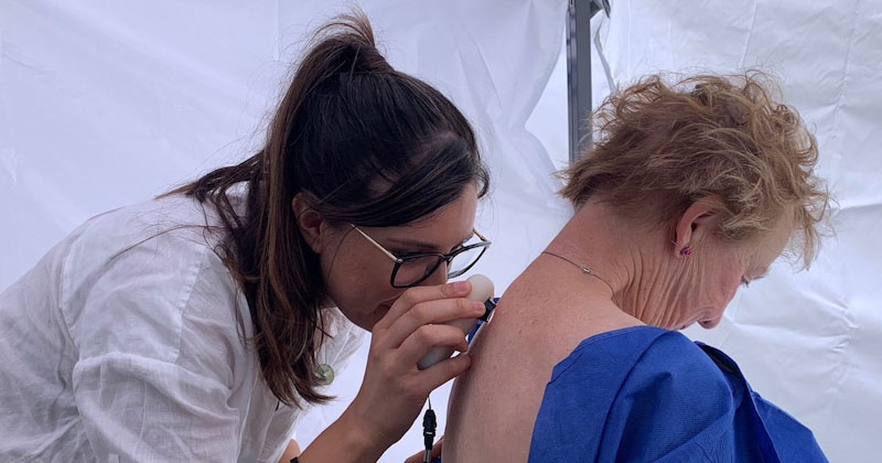 Clinician conducts mole check on female patient