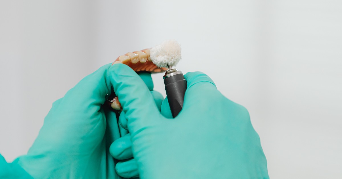Dentures held by hands in gloves