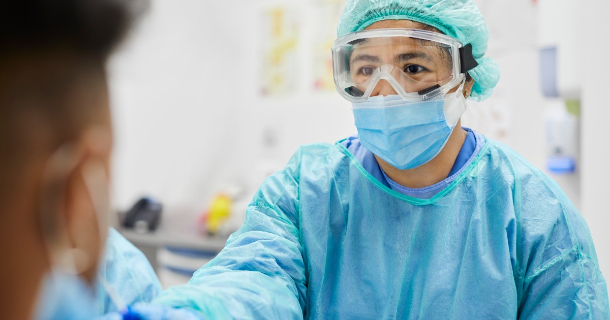 A doctor in protective gear gives a patient a COVD test
