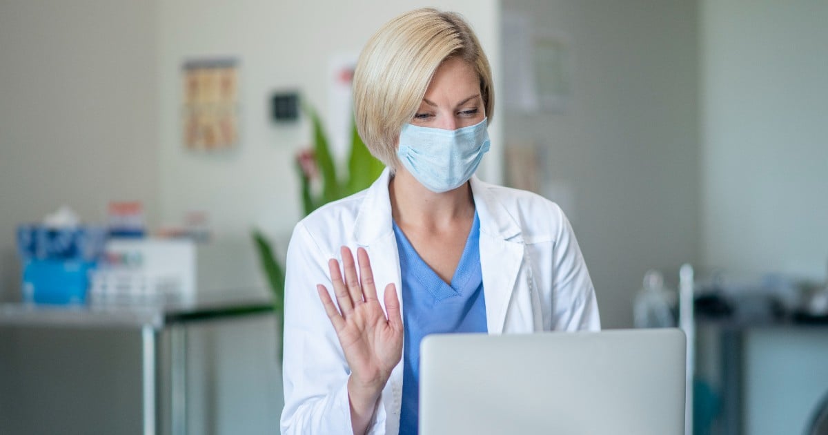 A clinician waving at a patient via video chat