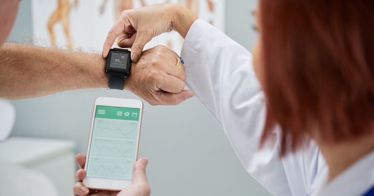 A doctor helping a patient set up a smartwatch and app.