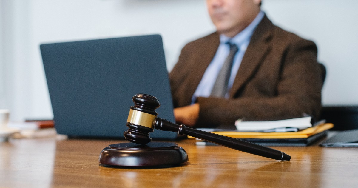 A gavel with a lawyer in the background