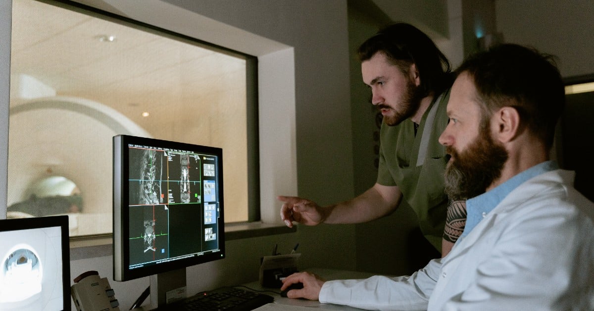 Two people look at diagnostic images on a screen