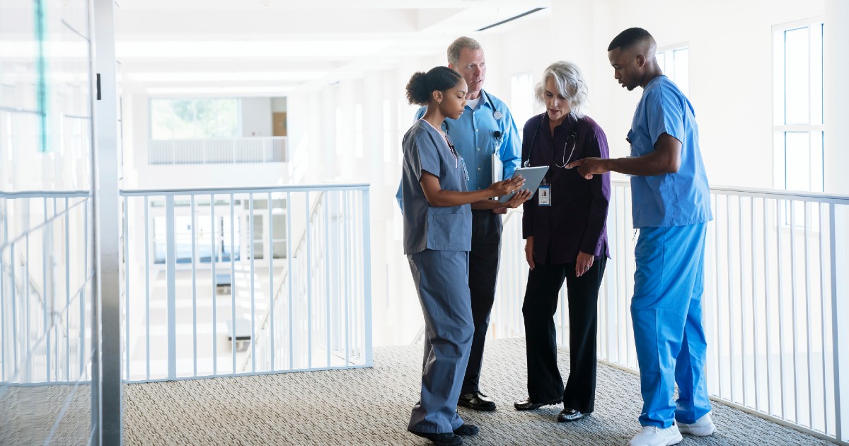 Nursing executives huddle with staff and discuss data on a tablet.