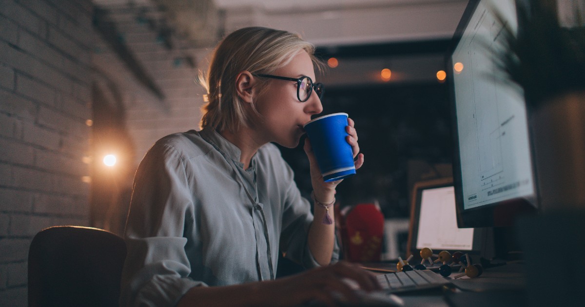 A person drinking coffee in front of a computer screen
