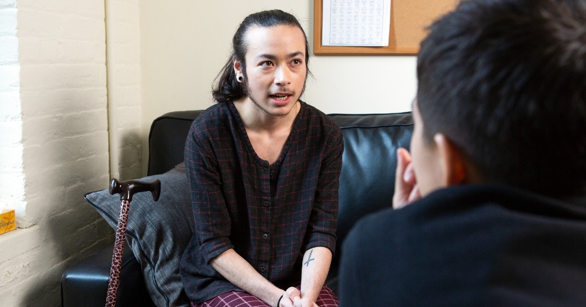 A person with a cane speaking to a healthcare provider