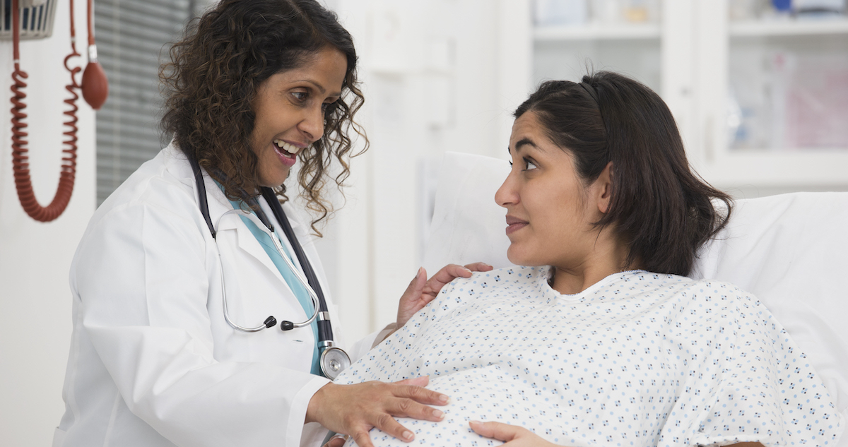 A pregnant patient talking with a doctor in a hospital.