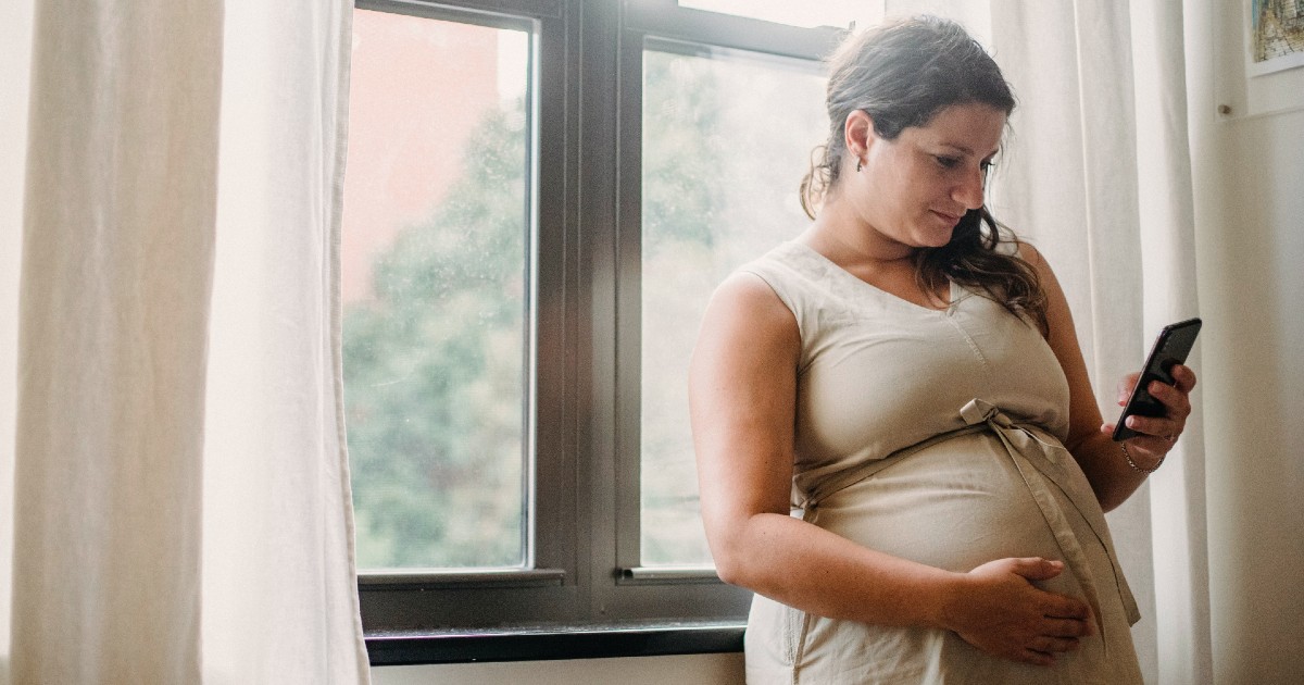 A pregnant person texting