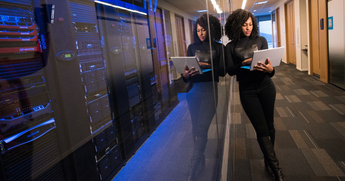 A security professional leans on a window to a server room