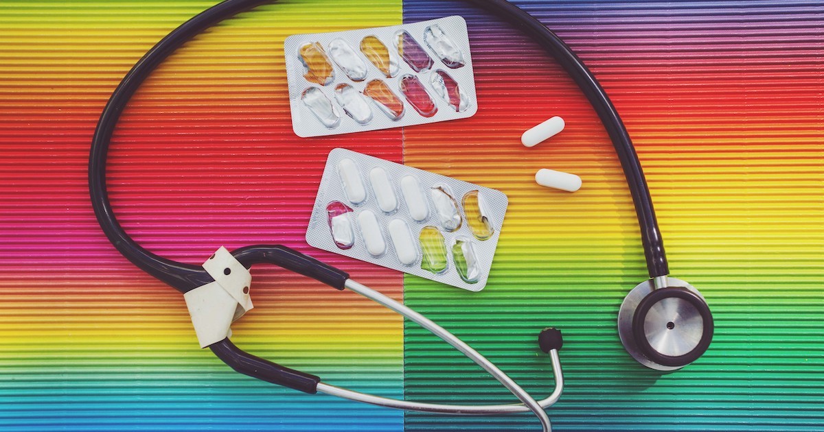 Stethoscope and pills on rainbow background