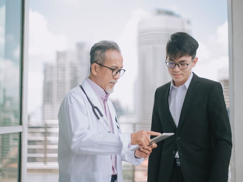 A doctor speaking with a person in a suit.