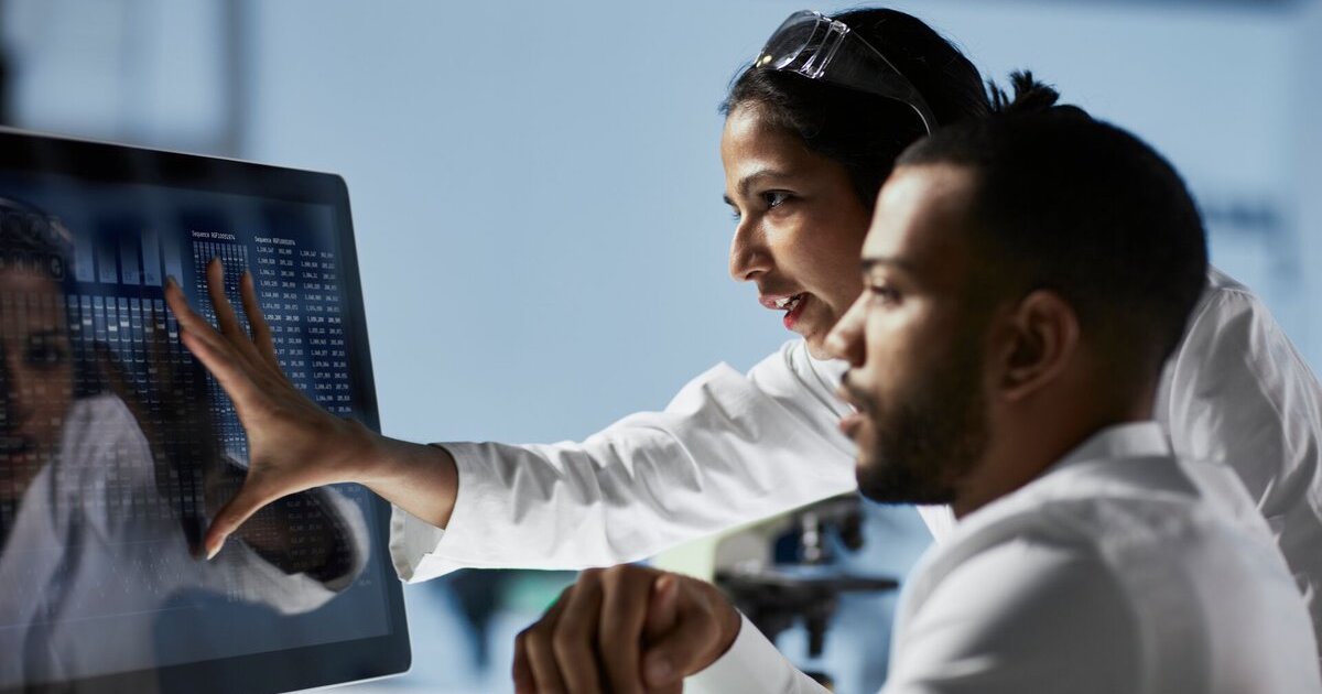 Two professionals examine computer screen