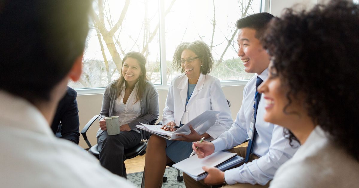 Smiling health system colleagues sit together and talk